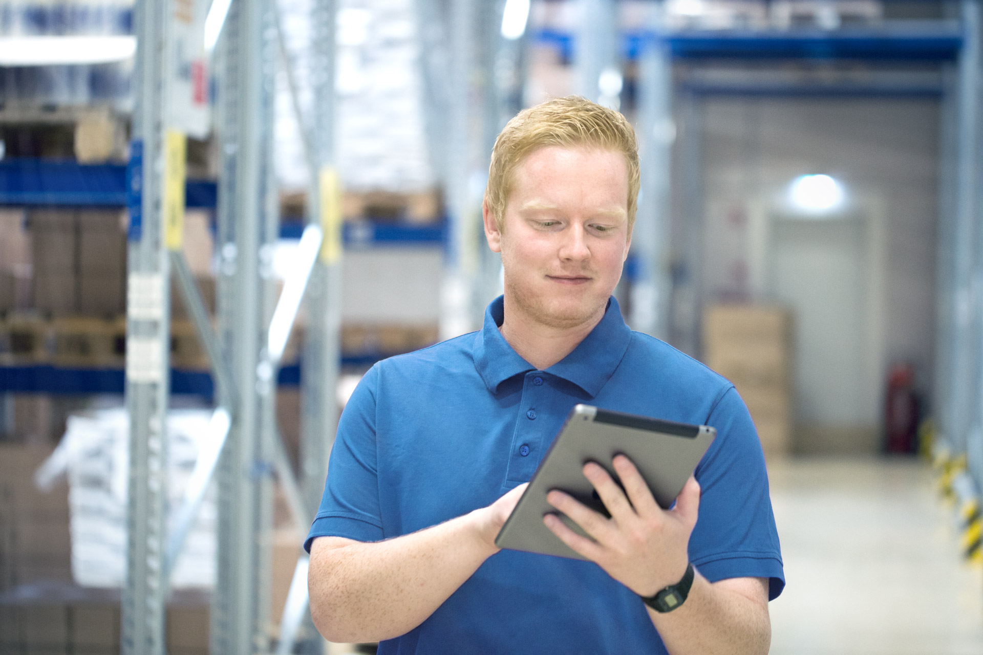 digitalisierung-arbeitsprozesse-weicon Ein Mann im blauen T-shirt steht im Lager und schaut auf ein Tablet